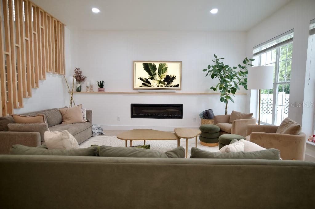 A living room features a linear fireplace, a wooden mantel, and a slatted wood staircase — 311 REEVES STREET, KISSIMMEE, FL