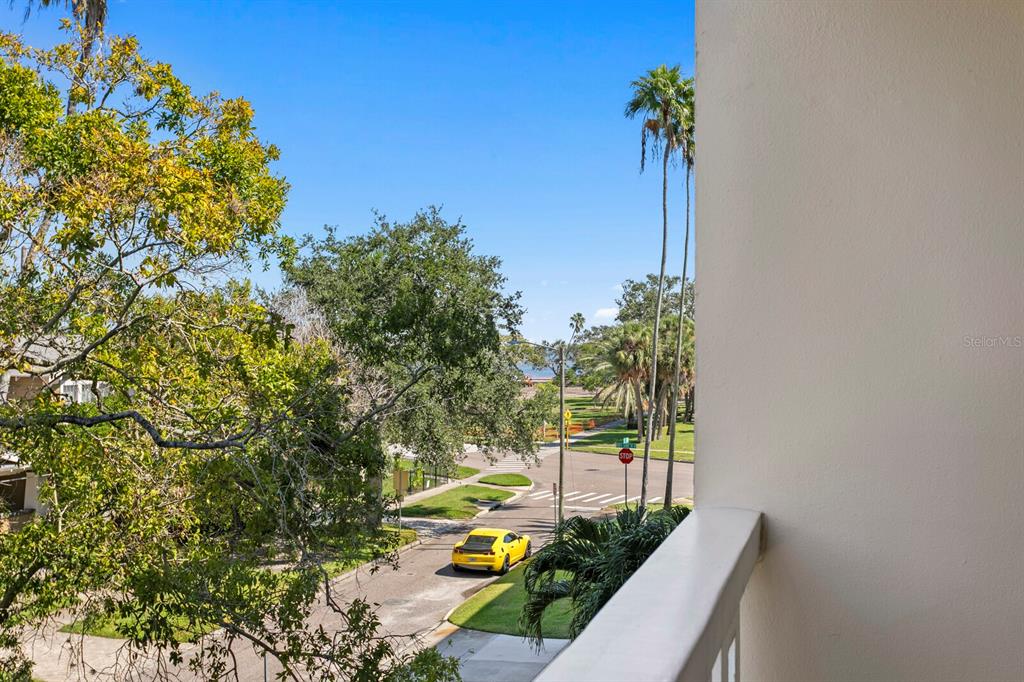 A view from a balcony overlooking a street with a yellow car and trees — 1200 N SHORE DRIVE NE UNIT 316, ST PETERSBURG, FL