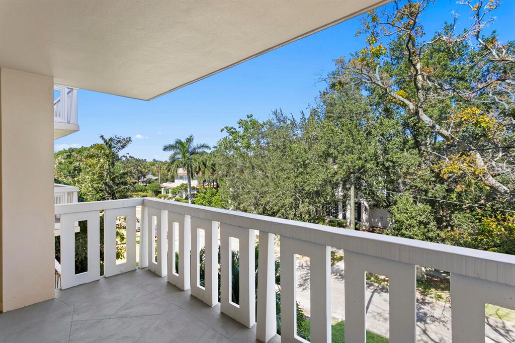 A balcony with a white railing overlooks trees and a residential street under a blue sky — 1200 N SHORE DRIVE NE UNIT 316, ST PETERSBURG, FL