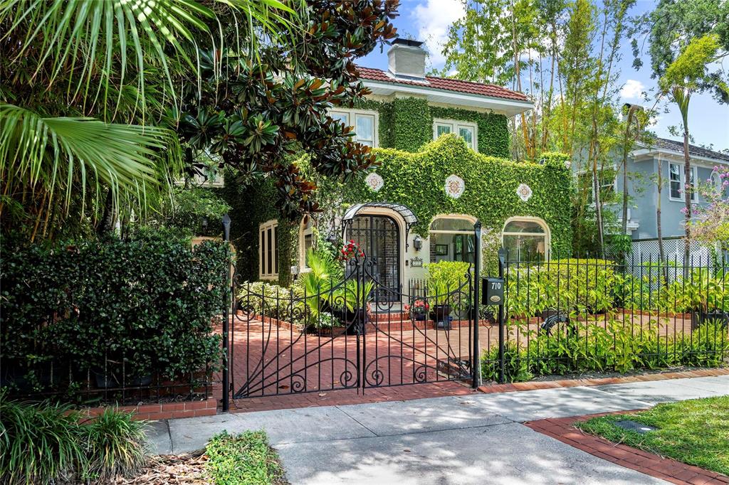 A two-story house covered in ivy sits behind a black wrought iron gate and fence — 710 SPRINGDALE ROAD, ORLANDO, FL