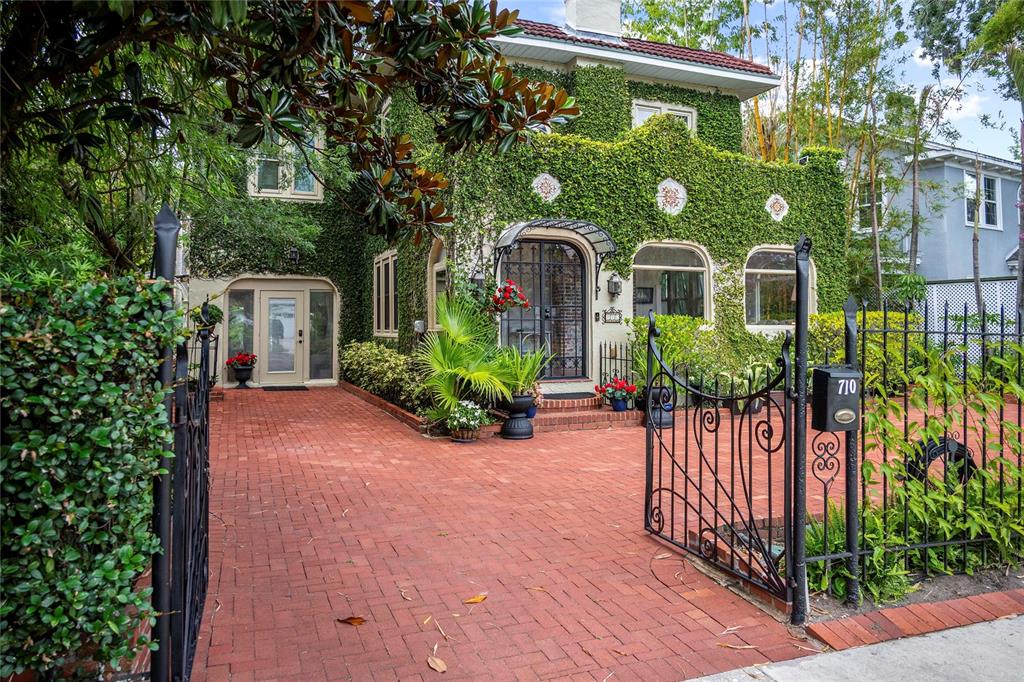A two-story house covered in ivy features a brick driveway and a black metal gate — 710 SPRINGDALE ROAD, ORLANDO, FL