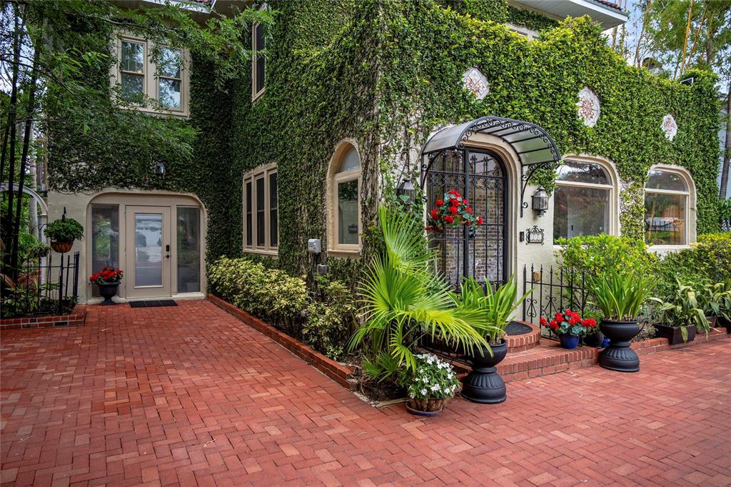 An ivy-covered house exterior features a brick patio, arched windows, and a wrought-iron entryway — 710 SPRINGDALE ROAD, ORLANDO, FL