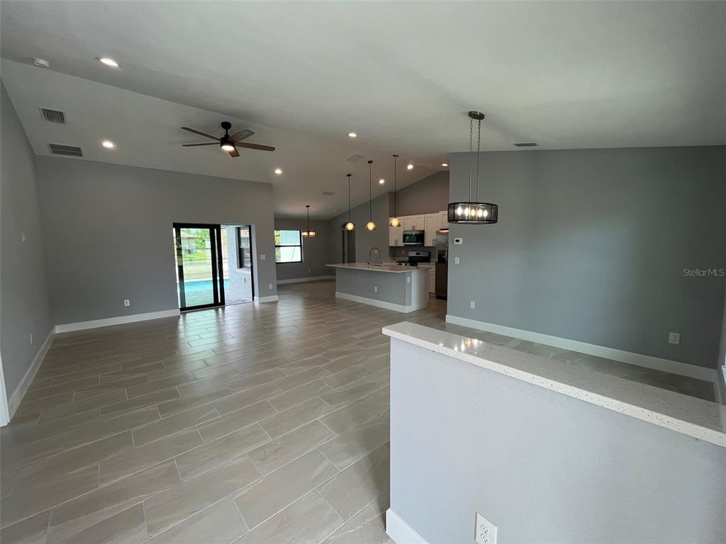 An open-concept living area features light tile flooring, a kitchen island, and gray walls — 13180 AMARYLLIS CIRCLE, PORT CHARLOTTE, FL