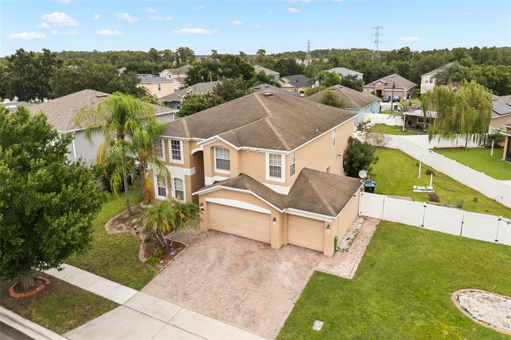 An aerial view of a two-story tan house with a three-car garage and driveway — 12657 IRIS LAKE DRIVE, ORLANDO, FL