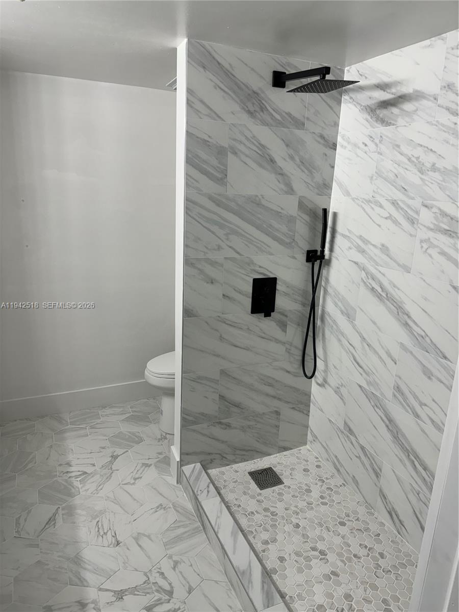 A bathroom features a walk-in shower with marble-look tile, black fixtures, and hexagonal floor tiles — 440 S Park Rd # 207, Hollywood FL 33021, HOLLYWOOD, FL