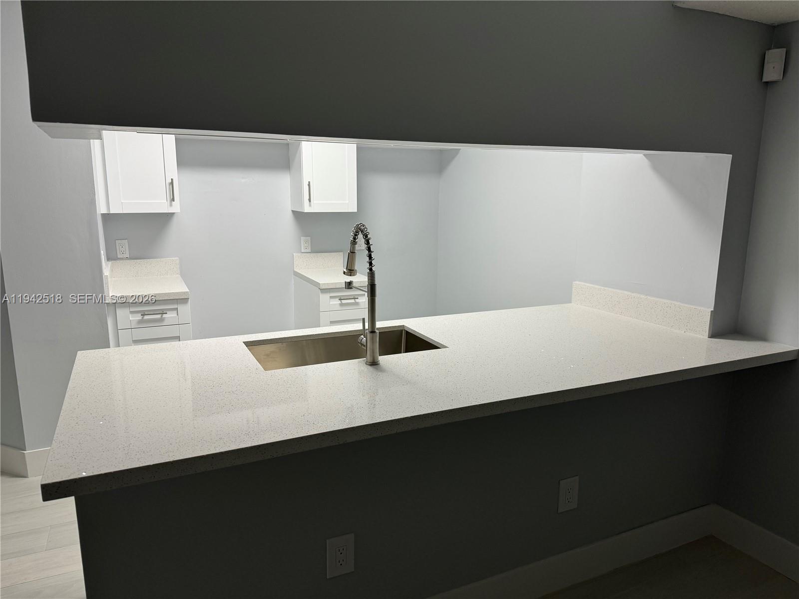 A kitchen features a white quartz countertop, a stainless steel sink, and white cabinets — 440 S Park Rd # 207, Hollywood FL 33021, HOLLYWOOD, FL