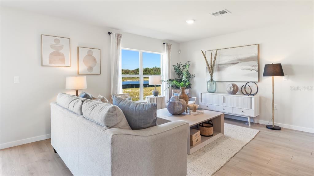A living room features a grey sofa, a coffee table, and a view of a pond — 1557 POWELL VALLEY DRIVE, PORT CHARLOTTE, FL