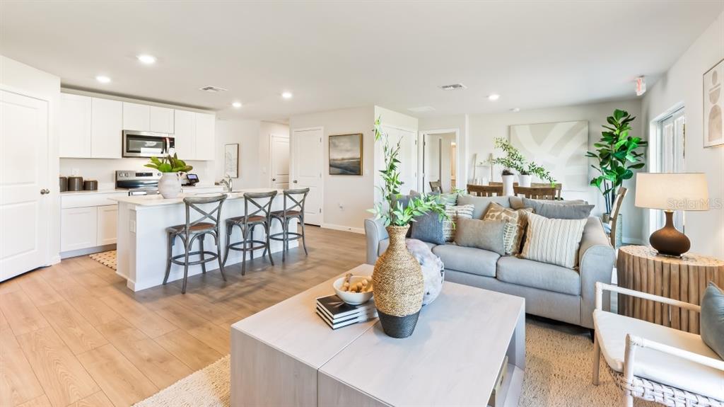 An open-concept kitchen and living area features white cabinetry, a kitchen island, and wood flooring — 1557 POWELL VALLEY DRIVE, PORT CHARLOTTE, FL