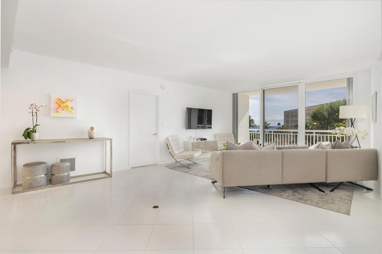 A bright living room features white tile floors, a beige sectional sofa, and a balcony view — 2780 S Ocean Boulevard # 311, Palm Beach FL 33480, PALM BEACH, FL