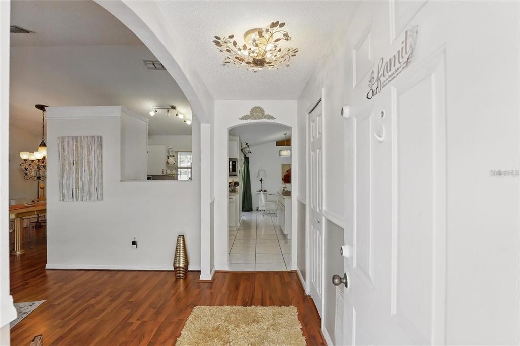 An entryway with wood flooring leads to a tiled kitchen area through an arched doorway — 417 JEFFERS STREET, DELTONA, FL