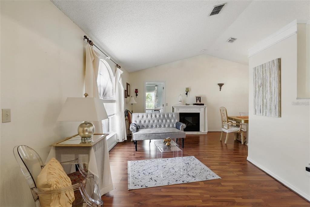 A living room with wood flooring, a fireplace, a silver sofa, and a vaulted ceiling — 417 JEFFERS STREET, DELTONA, FL