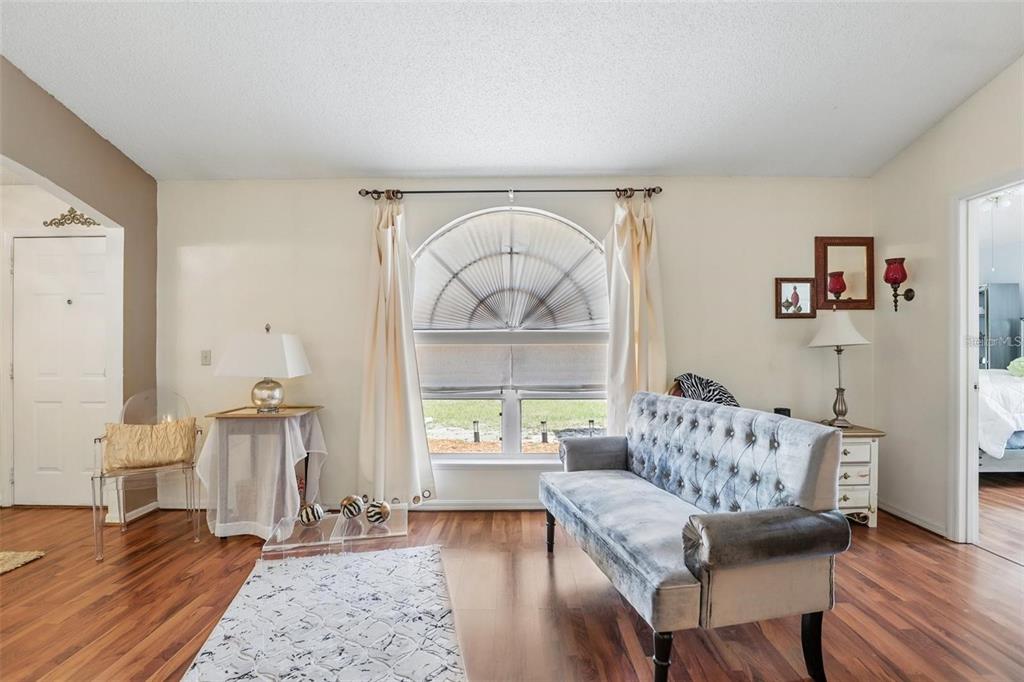 A living room features a tufted grey sofa, an arched window, and wood-look flooring — 417 JEFFERS STREET, DELTONA, FL