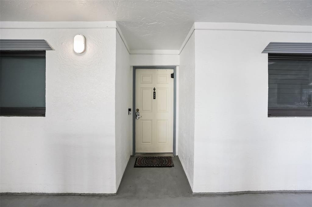 A white exterior door with a dark frame is centered between two windows — 5207 S ATLANTIC AVENUE UNIT 222, NEW SMYRNA BEACH, FL