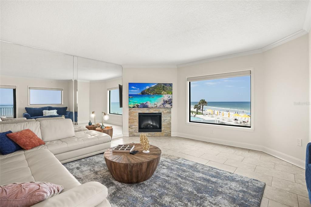 A living room features a stone fireplace, a large sectional sofa, and ocean views — 5207 S ATLANTIC AVENUE UNIT 222, NEW SMYRNA BEACH, FL