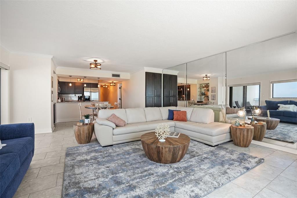 A living room features a large sectional sofa, a round wooden coffee table, and mirrored walls — 5207 S ATLANTIC AVENUE UNIT 222, NEW SMYRNA BEACH, FL