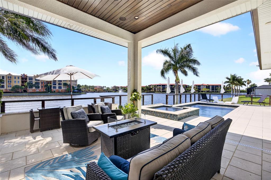 A covered patio features outdoor furniture, a fire pit, and a pool overlooking a lake — 125 COLONY POINT DRIVE, PUNTA GORDA, FL