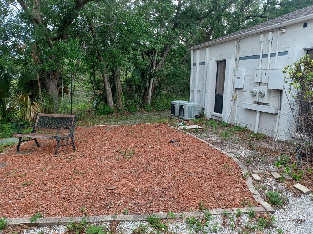 A backyard area features a wood-chip patio, a metal bench, and two air conditioning units — 13304 WINDING OAK COURT UNIT Front, TAMPA, FL
