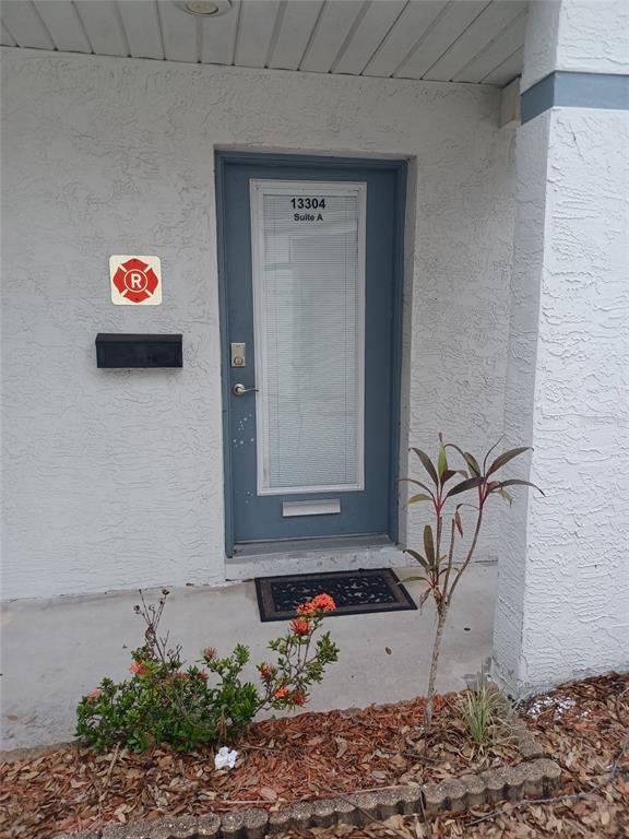 The exterior entrance features a blue door with a glass insert and a mailbox — 13304 WINDING OAK COURT UNIT Front, TAMPA, FL