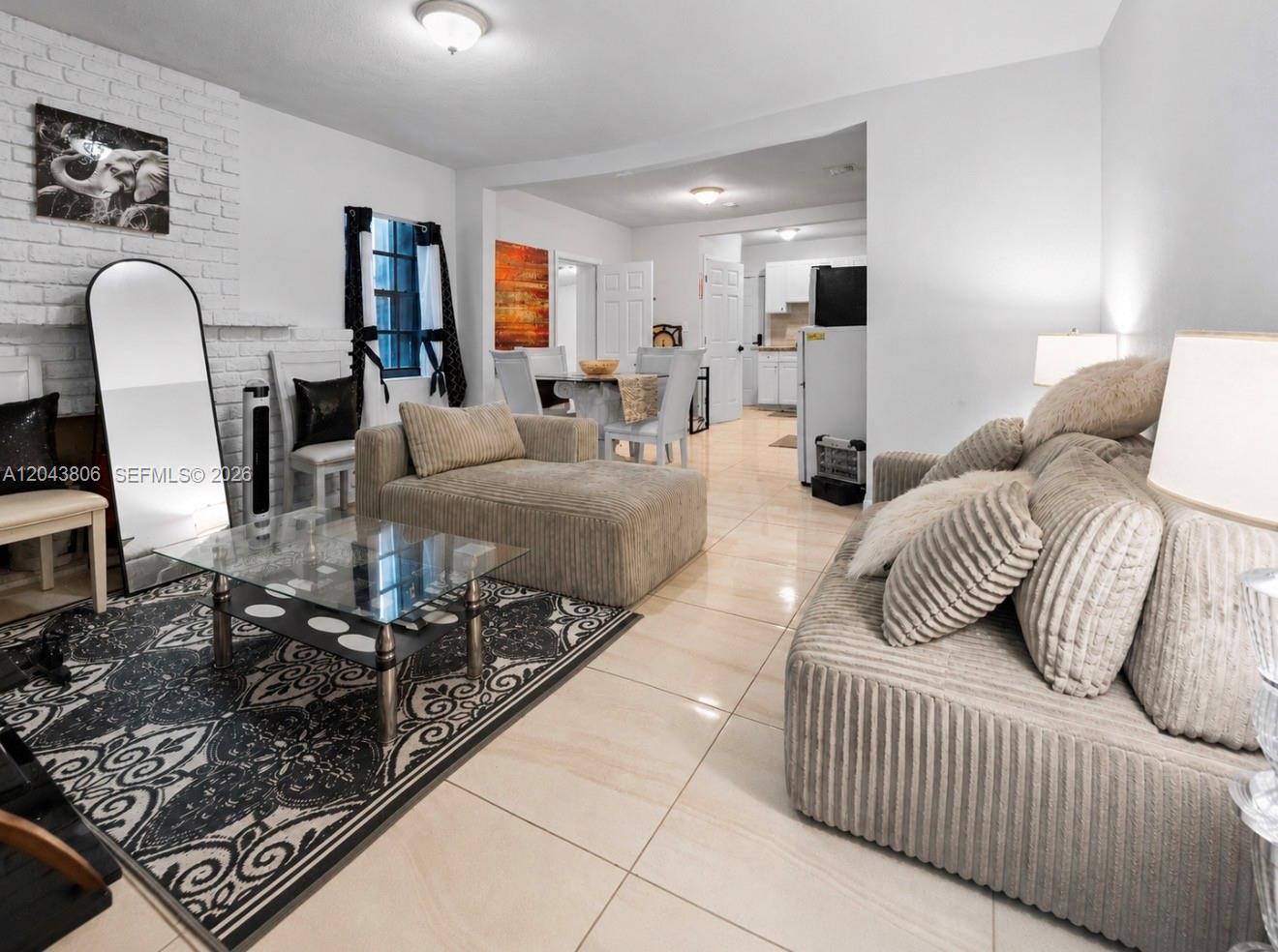 A living room features a white brick fireplace, tile flooring, and a glass coffee table — 7573 NW 12th Ct, Miami FL 33147, MIAMI, FL