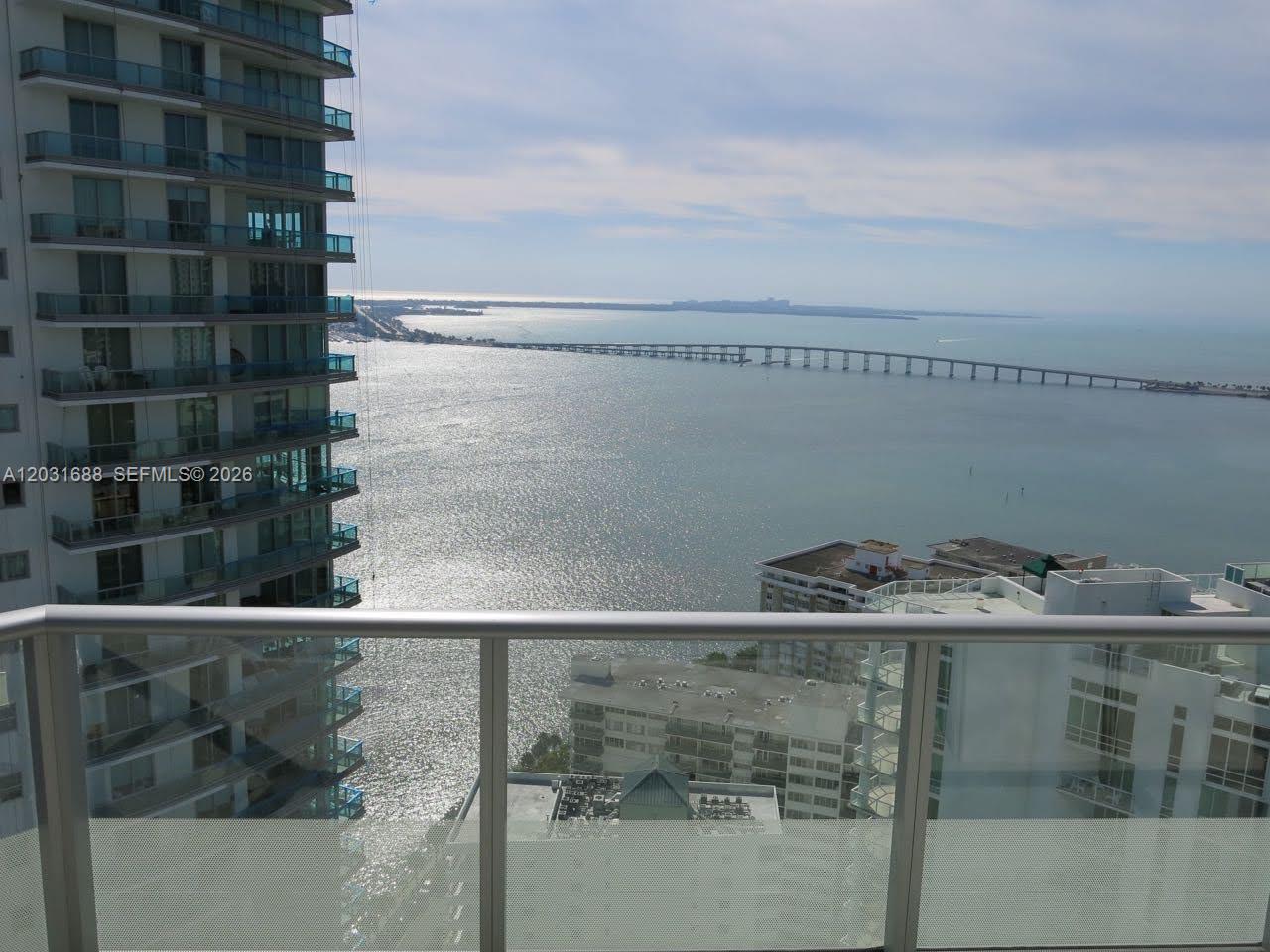 A high-rise balcony overlooks a bay with a long bridge and nearby residential buildings — 1300 Brickell Bay Dr # 3506, Miami FL 33131, MIAMI, FL