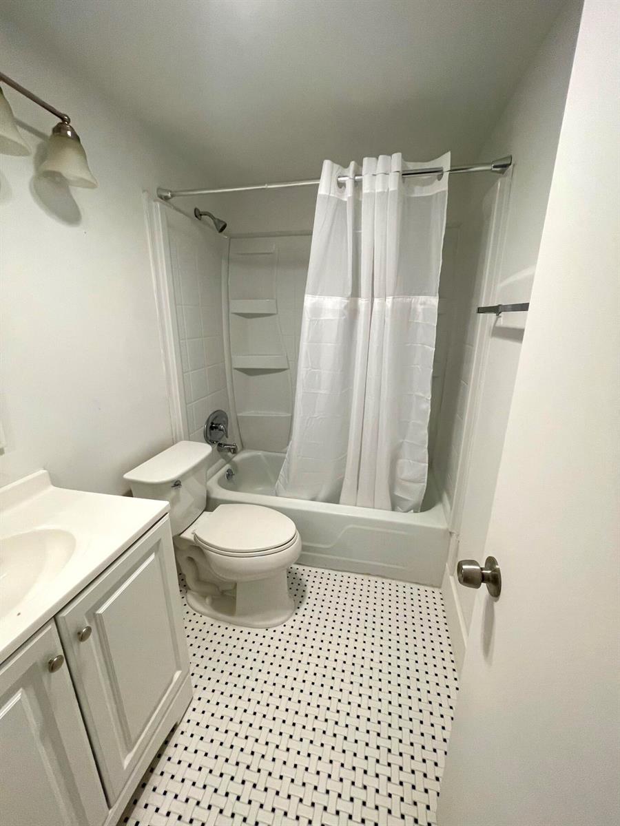 A small bathroom features a white vanity, a toilet, and a shower-tub combination — 203 Easthampton I, West Palm Beach FL 33417, WEST PALM BEACH, FL