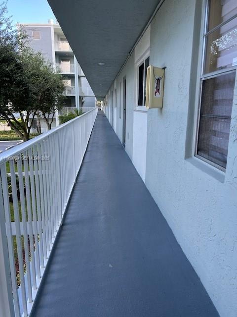An outdoor apartment building walkway with a white railing and a light-colored exterior wall — 2226 N Cypress Bend Dr # 210, Pompano Beach FL 33069, POMPANO BEACH, FL