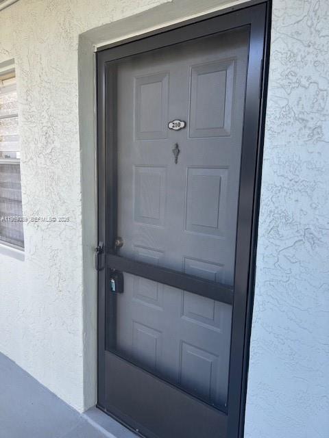 A gray front door with a black screen door and the number 210 attached — 2226 N Cypress Bend Dr # 210, Pompano Beach FL 33069, POMPANO BEACH, FL