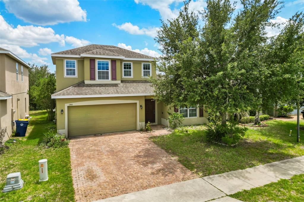 A two-story house with a brick paver driveway, a two-car garage, and a large tree — 1300 CAVENDER CREEK RD, MINNEOLA, FL