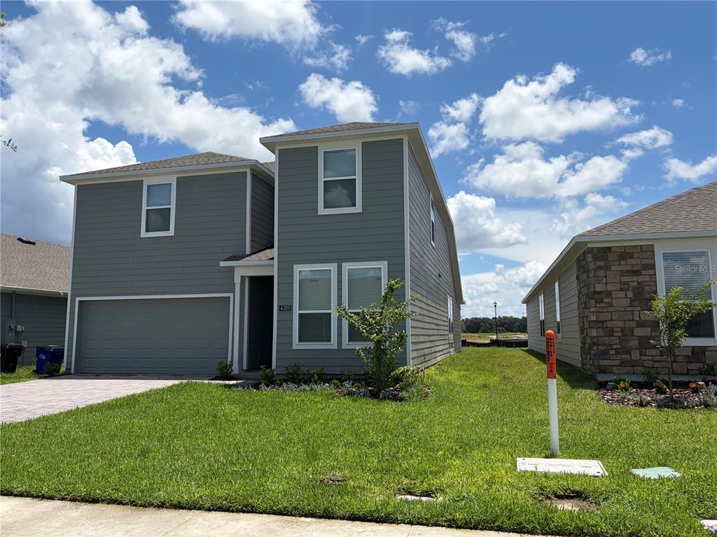 A two-story house with gray horizontal siding, a two-car garage, and a front lawn — 4389 VIBERNUM AVENUE, ST CLOUD, FL