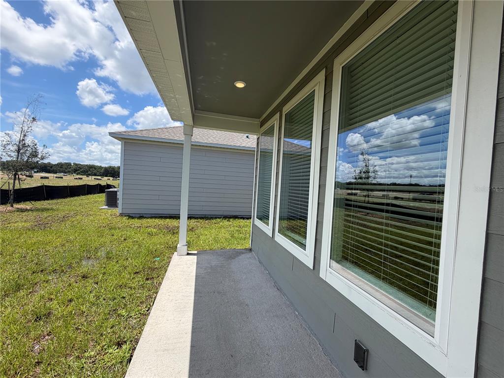 A covered concrete patio overlooks a grassy yard and a neighboring house — 4389 VIBERNUM AVENUE, ST CLOUD, FL