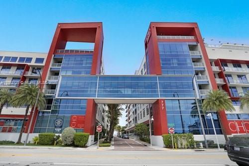 A modern multi-story commercial building with a glass bridge connecting two red-accented towers — 777 N Ocean Dr # S216, Hollywood FL 33019, HOLLYWOOD, FL