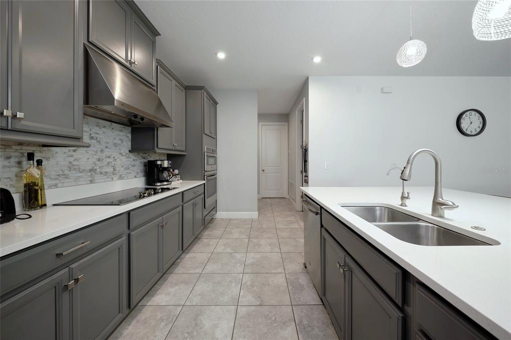 A kitchen features gray cabinets, white countertops, stainless steel appliances, and light tile flooring — 3081 AGOSTINO TERRACE, KISSIMMEE, FL