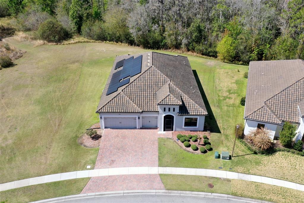 An aerial view shows a single-story house with a tiled roof, solar panels, and driveway — 3081 AGOSTINO TERRACE, KISSIMMEE, FL