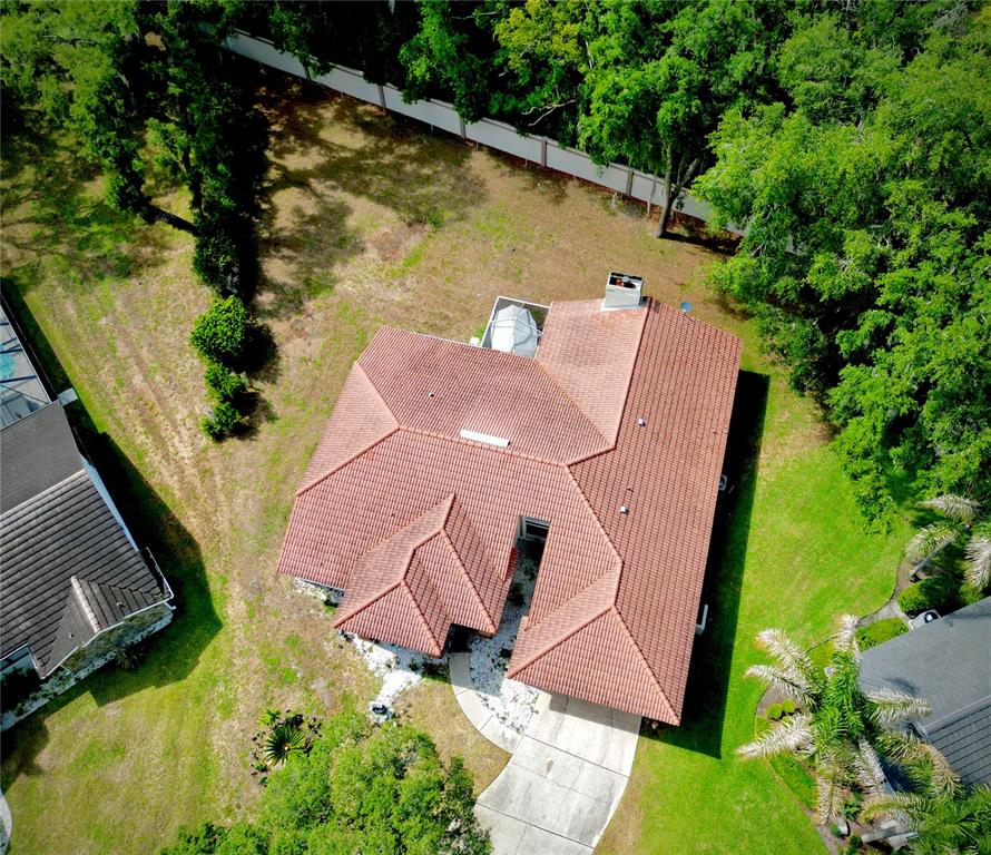 An aerial view shows a house with a red tile roof and a concrete driveway — 5455 PINE BARK LANE, WESLEY CHAPEL, FL