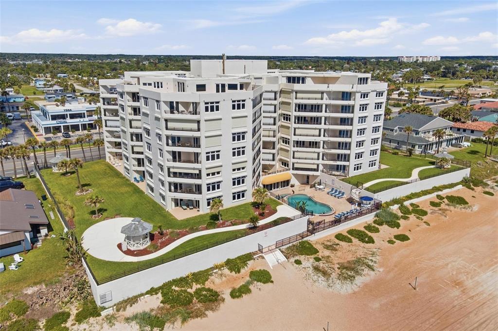 An aerial view of a multi-story beachfront condominium building with a pool and gazebo — 395 S ATLANTIC AVENUE UNIT 402, ORMOND BEACH, FL