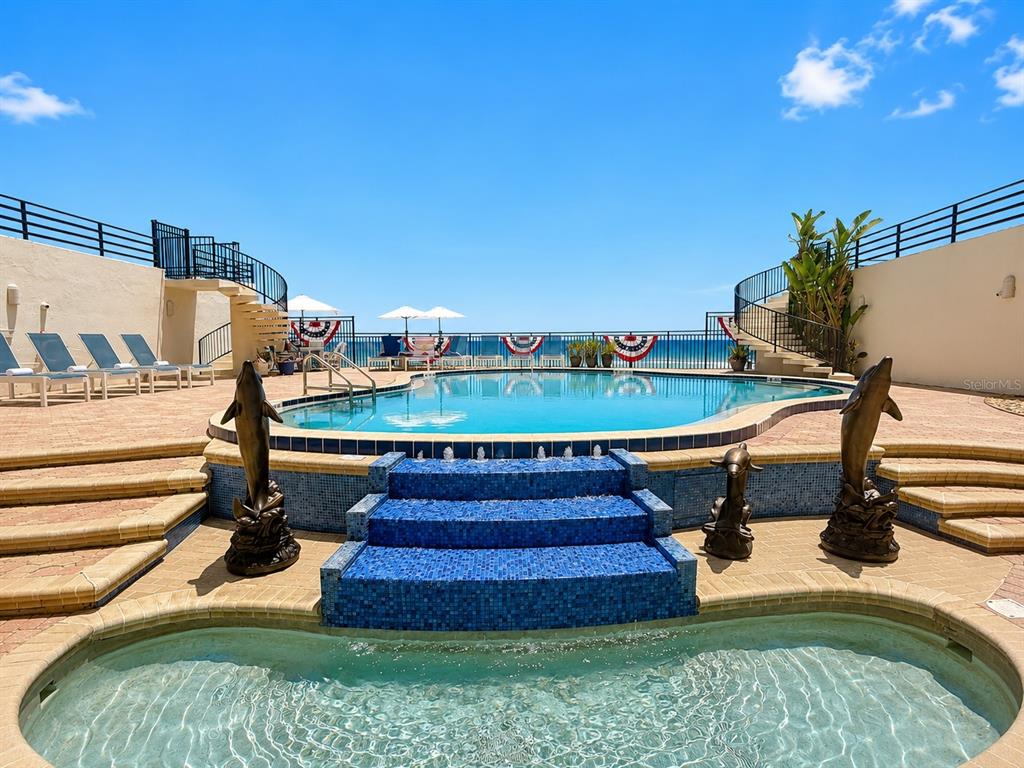 A swimming pool and hot tub overlook the ocean from a paved patio area — 395 S ATLANTIC AVENUE UNIT 402, ORMOND BEACH, FL