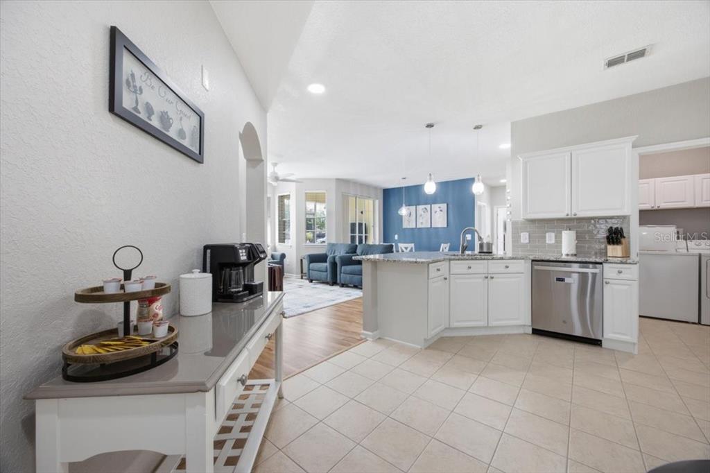 A kitchen with white cabinets and a stainless steel dishwasher opens into a living area — 301 TERRACE RIDGE CIRCLE UNIT 301, DAVENPORT, FL