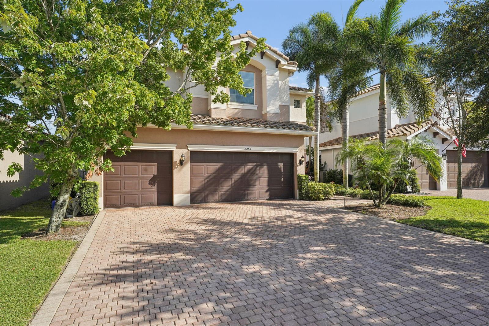 A two-story house with a three-car garage and a paved driveway sits under palm trees — 8256 Savara Streams Lane, Boynton Beach FL 33473, BOYNTON BEACH, FL
