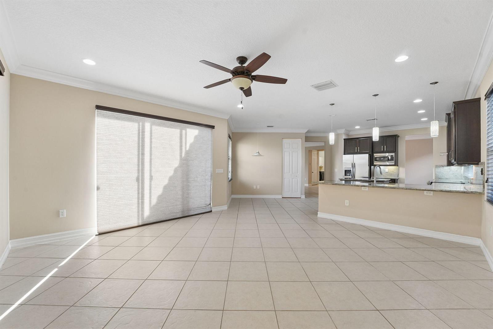 An open-concept living and kitchen area features beige tile flooring and a ceiling fan — 8256 Savara Streams Lane, Boynton Beach FL 33473, BOYNTON BEACH, FL
