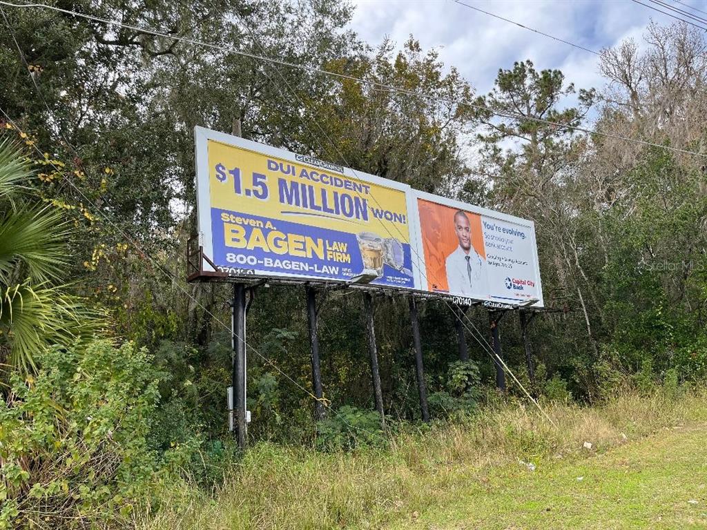 A large billboard stands in a wooded area advertising a law firm and a bank — 1602A SW WILLISTON ROAD, GAINESVILLE, FL