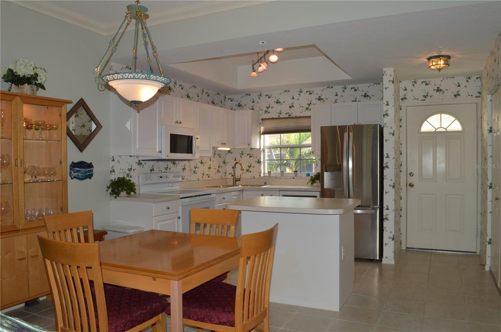 A kitchen with white cabinets, stainless steel appliances, a dining table, and floral wallpaper — 8370 WINGATE DRIVE UNIT 717, SARASOTA, FL