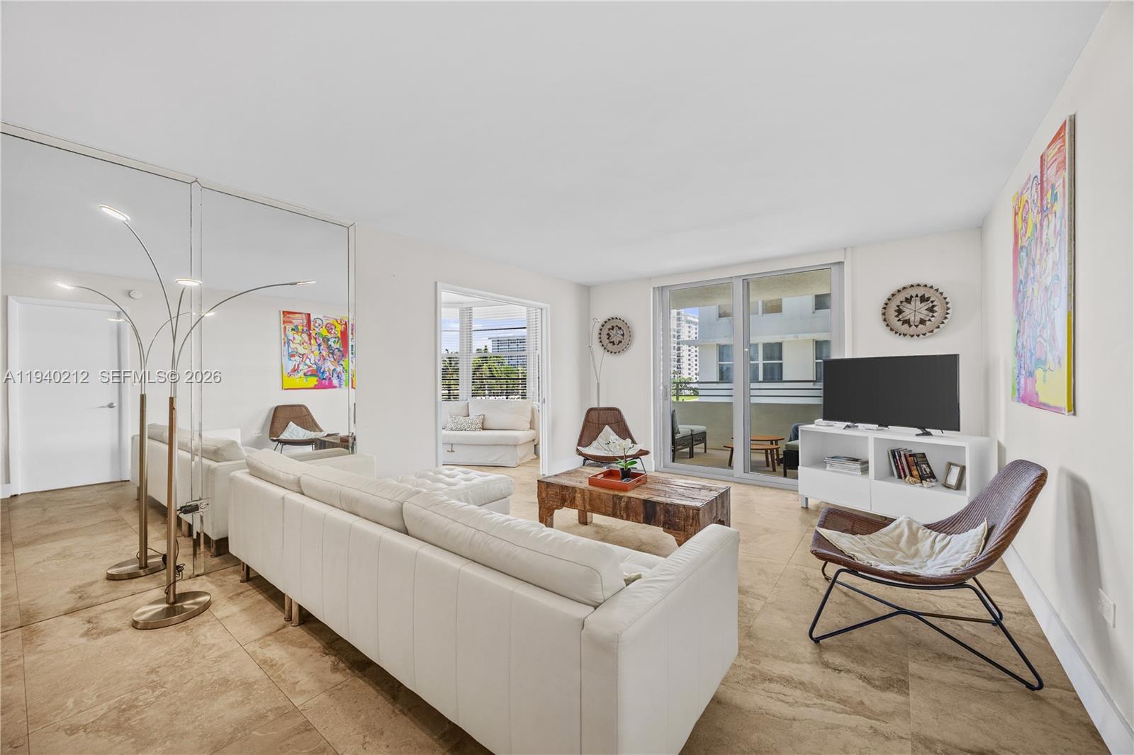 A living room features a white sofa, a wooden coffee table, and a mirrored wall — 5555 Collins Ave # 4B, Miami Beach FL 33140, MIAMI BEACH, FL