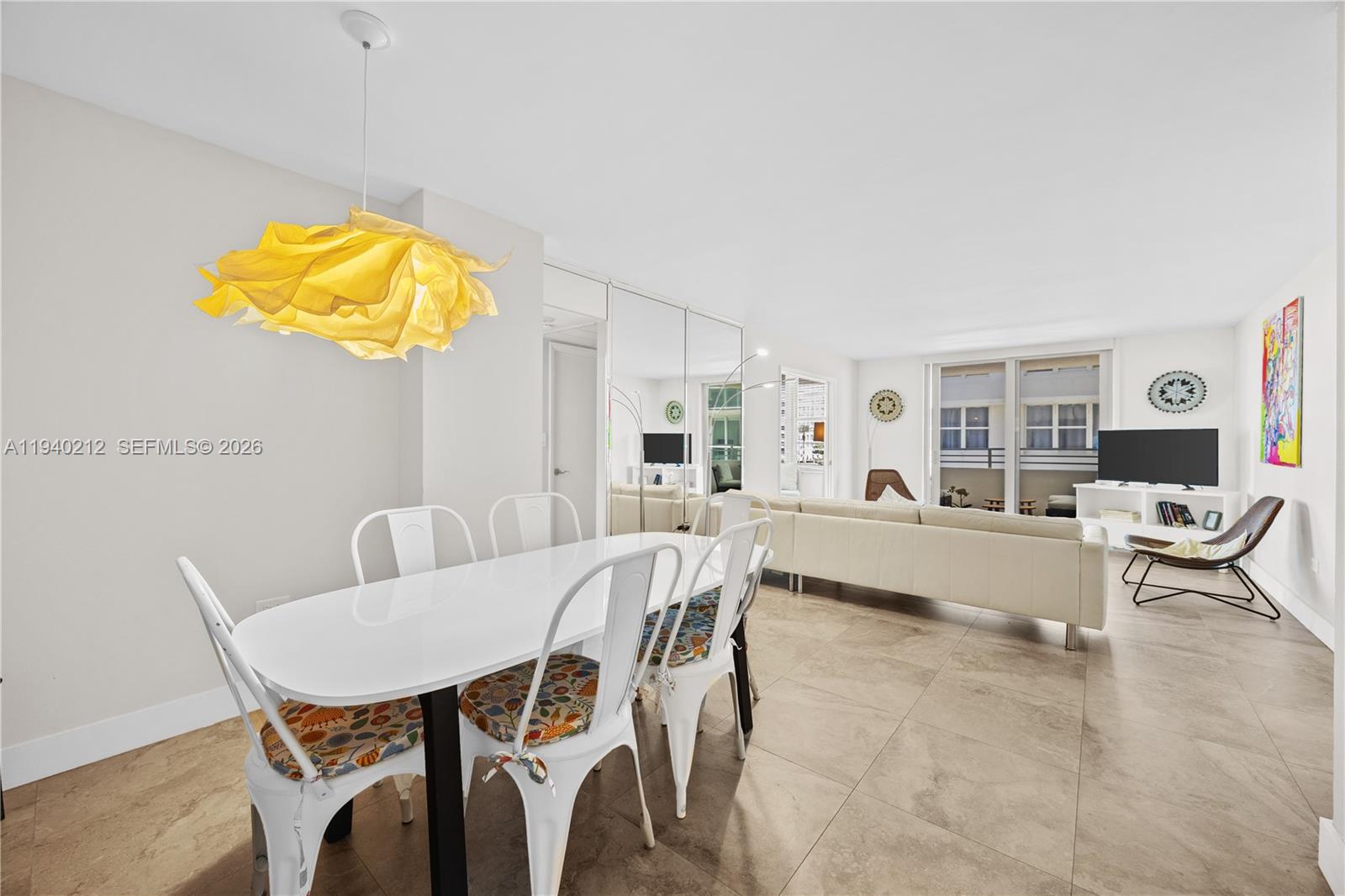 A dining area with a yellow pendant light opens into a living room with tile floors — 5555 Collins Ave # 4B, Miami Beach FL 33140, MIAMI BEACH, FL