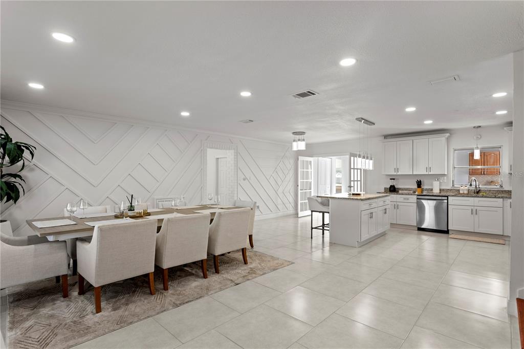 A modern kitchen with white cabinetry, a granite island, and an adjacent dining area — 8702 ELMWOOD LANE, TAMPA, FL