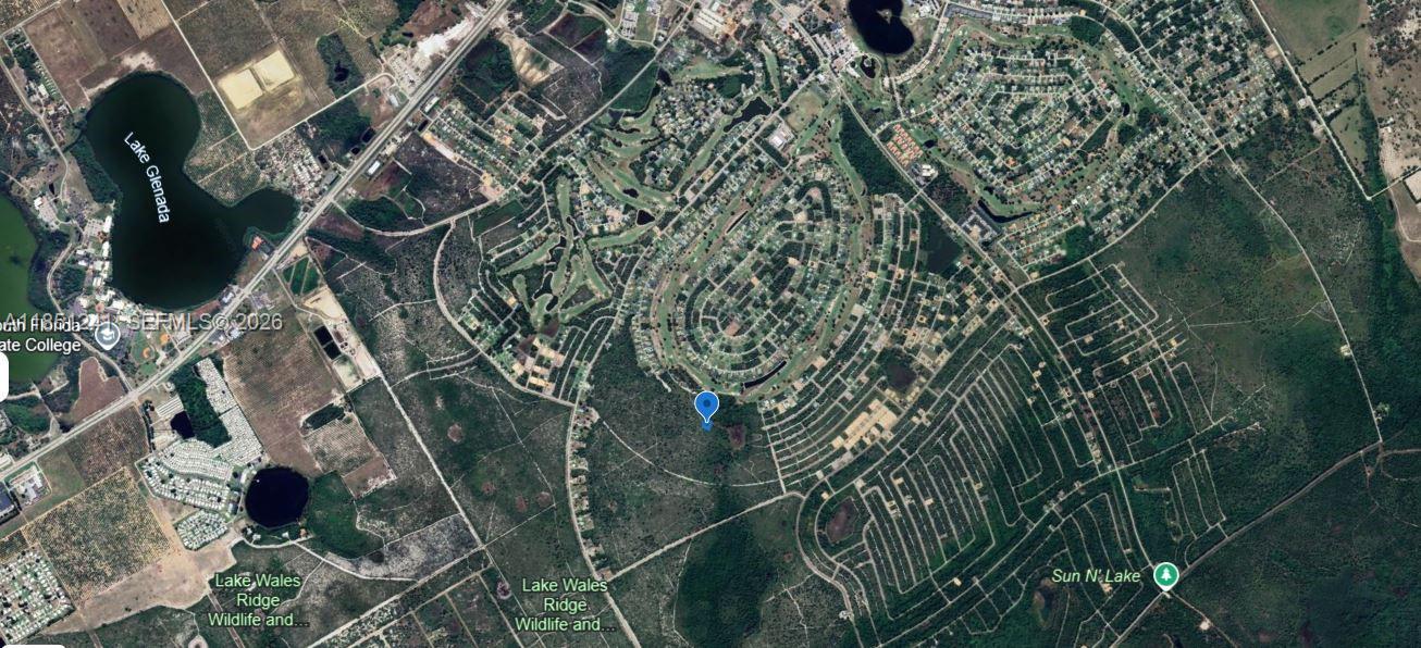 An aerial view shows a golf course green surrounded by water near a clubhouse building — 6579 San Bruno Dr, Sebring FL 33872, SEBRING, FL