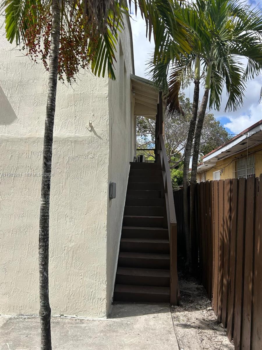 An exterior view shows a wooden staircase leading to an upper level beside a building — 2908 NW 14 ct # 1, Miami FL 33142, MIAMI, FL