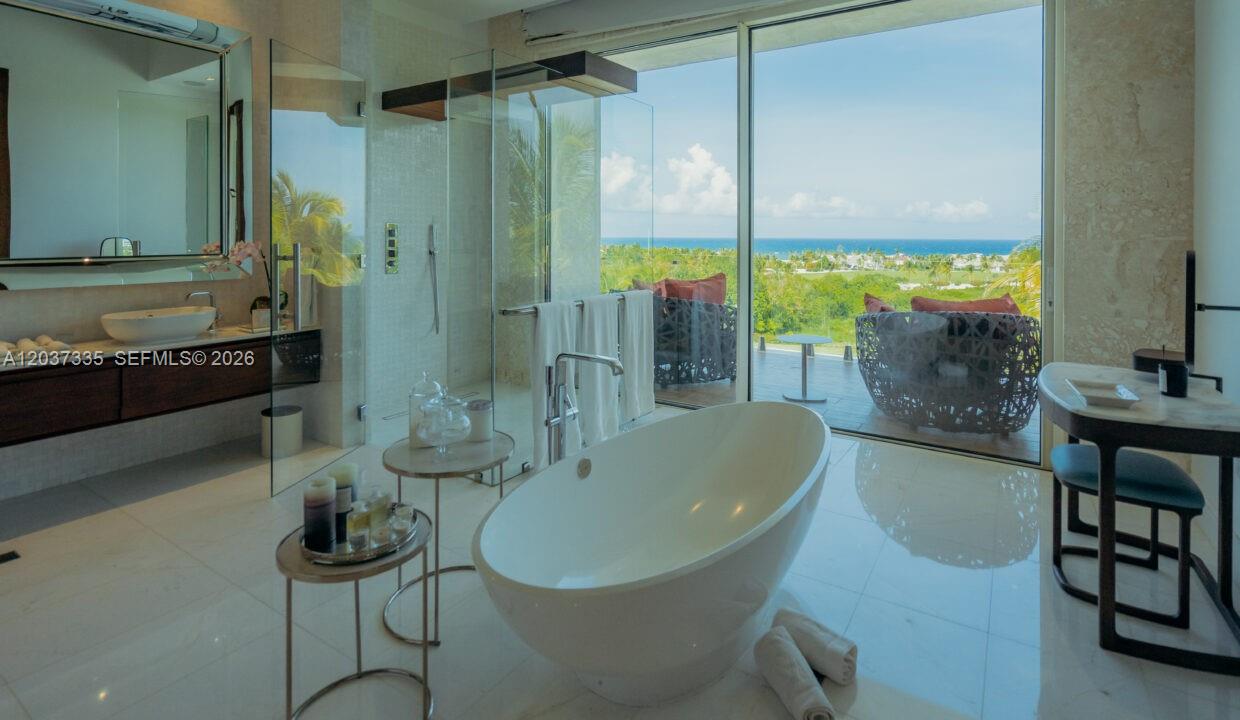 A modern bathroom features a freestanding tub, glass shower, and floor-to-ceiling windows overlooking the ocean — 0 Fundadores de golf, FL, FL