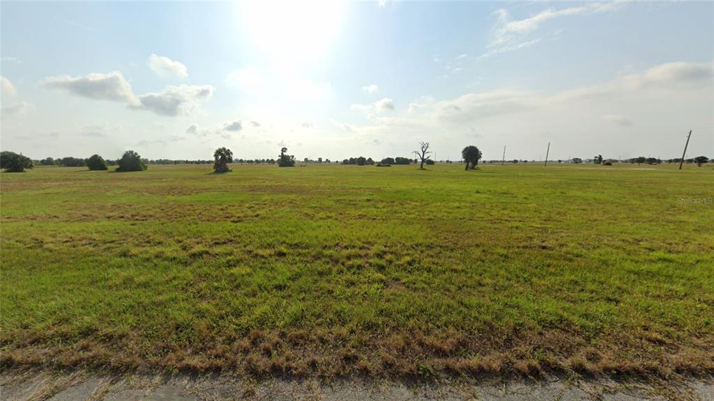 A wide, flat, grassy vacant lot under a bright, partly cloudy sky — 10 PINE LANE, PLACIDA, FL