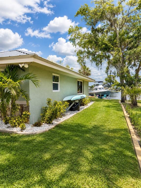The exterior of a light green house with a metal roof and a grassy yard — 5431 FOLEY SQUARE, NEW PORT RICHEY, FL