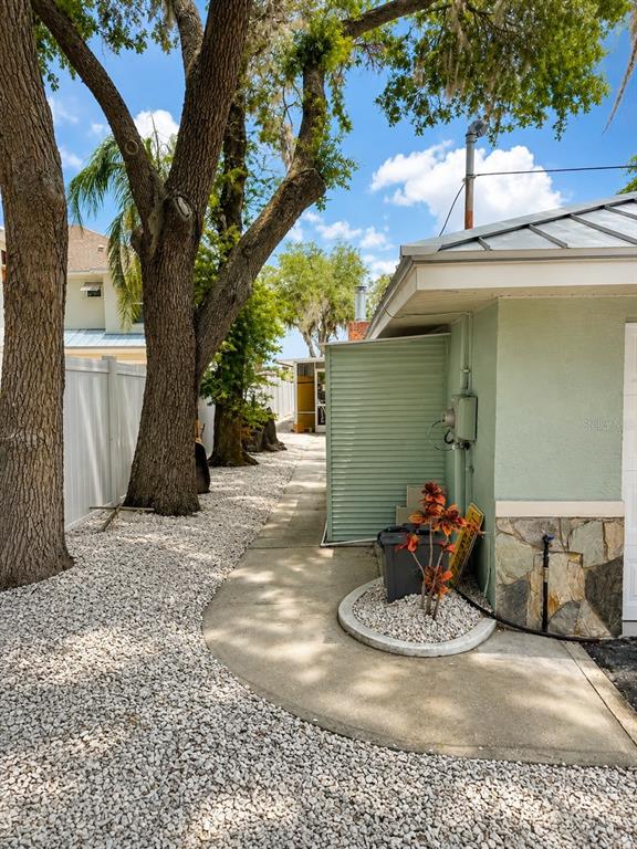 A concrete walkway leads past a light green building with a stone base and trees — 5431 FOLEY SQUARE, NEW PORT RICHEY, FL